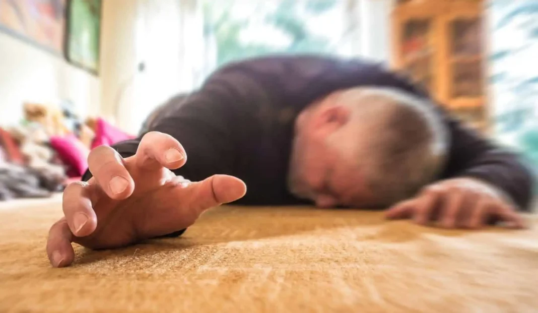 A man lies on the floor, resting with his hands placed flat against the surface.